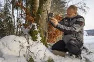 Photo d'un agent de l'OFB posant un piège photographique
