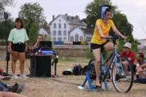 Photo d'une spectatrice intégrée dans le spectacle pour faire fonctionner un vélo générateur d'électricité