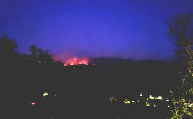 Paysage de nuit où l'on voit au loin un incendie.