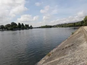 La photo met l'accent sur la Seine et des berges très bétonnées, sans aucune végétation. On aperçoit des arbres sur les berges au fond, au loin.