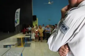Photo d'un agent de l’OFB, de dos, qui assiste à un rassemblement officiel, avec un groupe de personnes réunies en arrière-plan dans une salle
