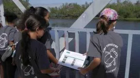 Cinq enfants sont en train de réaliser un diagnostic de l'étang de Saint Paul à la Réunion