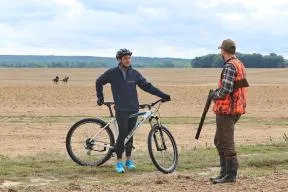 Photo d'échanges entre un cycliste et un chasseur