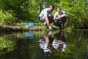 Deux agents effectuent un prélèvement d'eau pour l'analyser