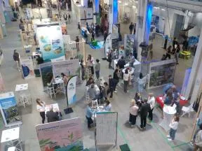 Dans un salon professionnel en intérieur et composé de plusieurs stands, on voit le stand de l'OFB avec plusieurs agents en interaction avec le public