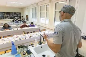 Un agent de l'OFB vue de dos s'exprime face à des élèves, dans une salle de classe 