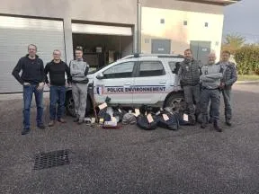 6 agents de la police de l'environnement placés à côté d'un véhicule sérigraphié. Au centre de la photo, des sacs plastiques contenant de la venaison saisie. Une carabine saisie figure également sur la photographie.