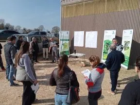 Photo présentant des agents de l'OFB en extérieur dans une exploitation agricole. Les agents d'expriment devant une dizaines de personnes sur la base de kakémonos traitant de l'intérêt des haies.