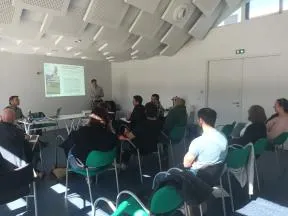 Photo représentant deux agents de l'OFB en train de réaliser une présentation devant une dizaine de personnes assises sur des chaises