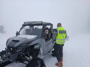 Dans un paysage de montagne enneigé, un agent de l'OFB contrôle la circulation d'une motoneige