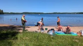 Photo : un agent de l'OFB et un agent de l'ONF contrôlent des usagers de la nature près d'un lac.