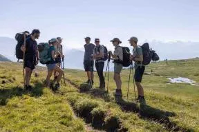 En montagne, un groupe de 4 agents contrôleurs échange avec un groupe de 3 randonneurs. Le contrôle se déroule dans le calme, les personnes sourient.