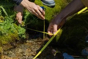 Mains d'agents dans un cours d'eau qui mesure sa largeur