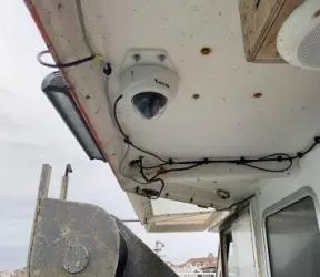 Photo du plafond d'une casquette de bateau sur laquelle est fixée une caméra dôme, elle surplombe une straucture en métal dont une partie est visible (le vire-filet)