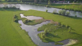 Photo aérienne d'une zone humide, bras d'eau en parrlèle de la rivière, entourées de prairies 